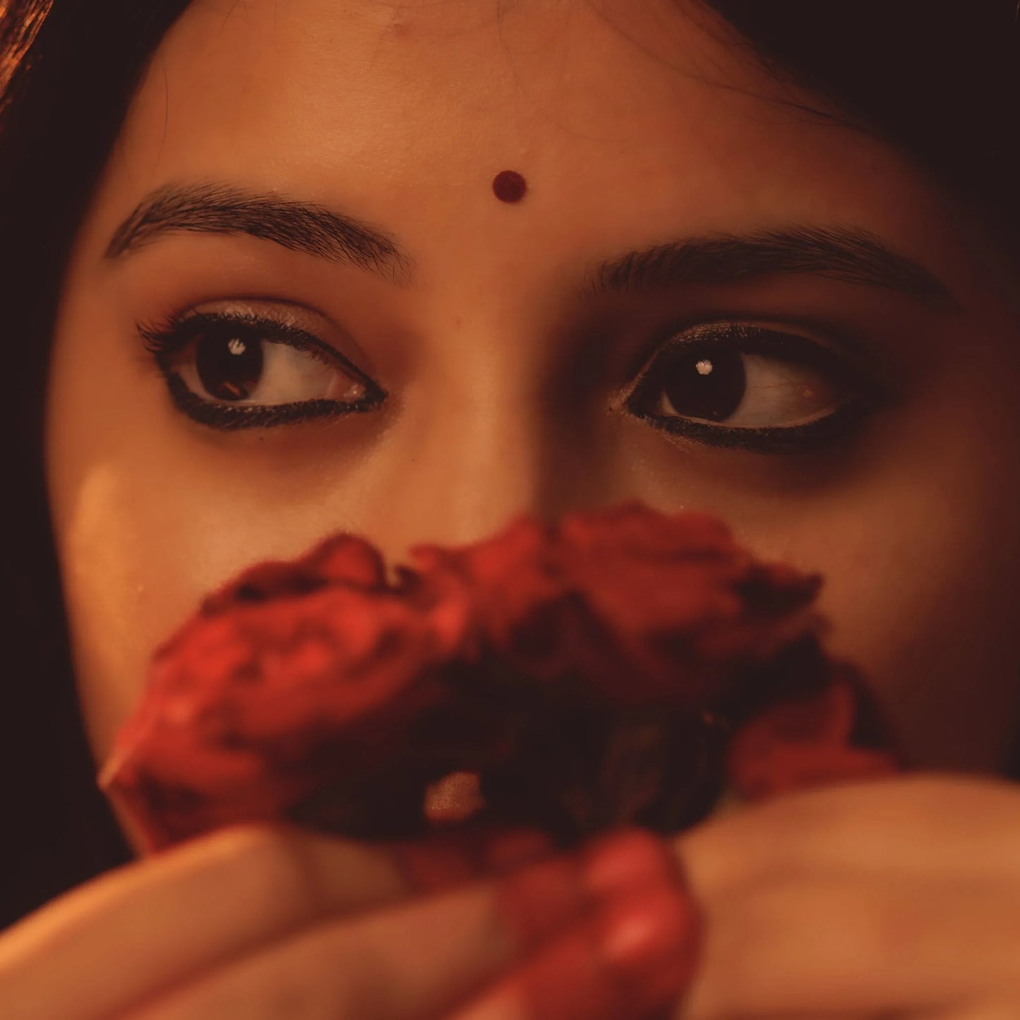 Close-up of a woman holding a red roses with a warm colour tone.