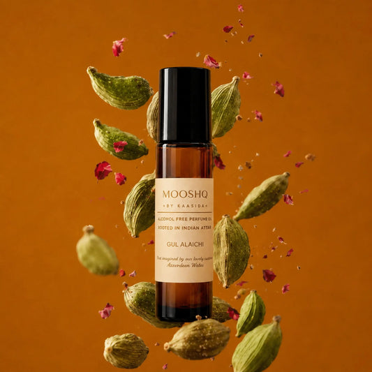 Mooshq perfume bottle with cardamom pods and rose petals on an orange background