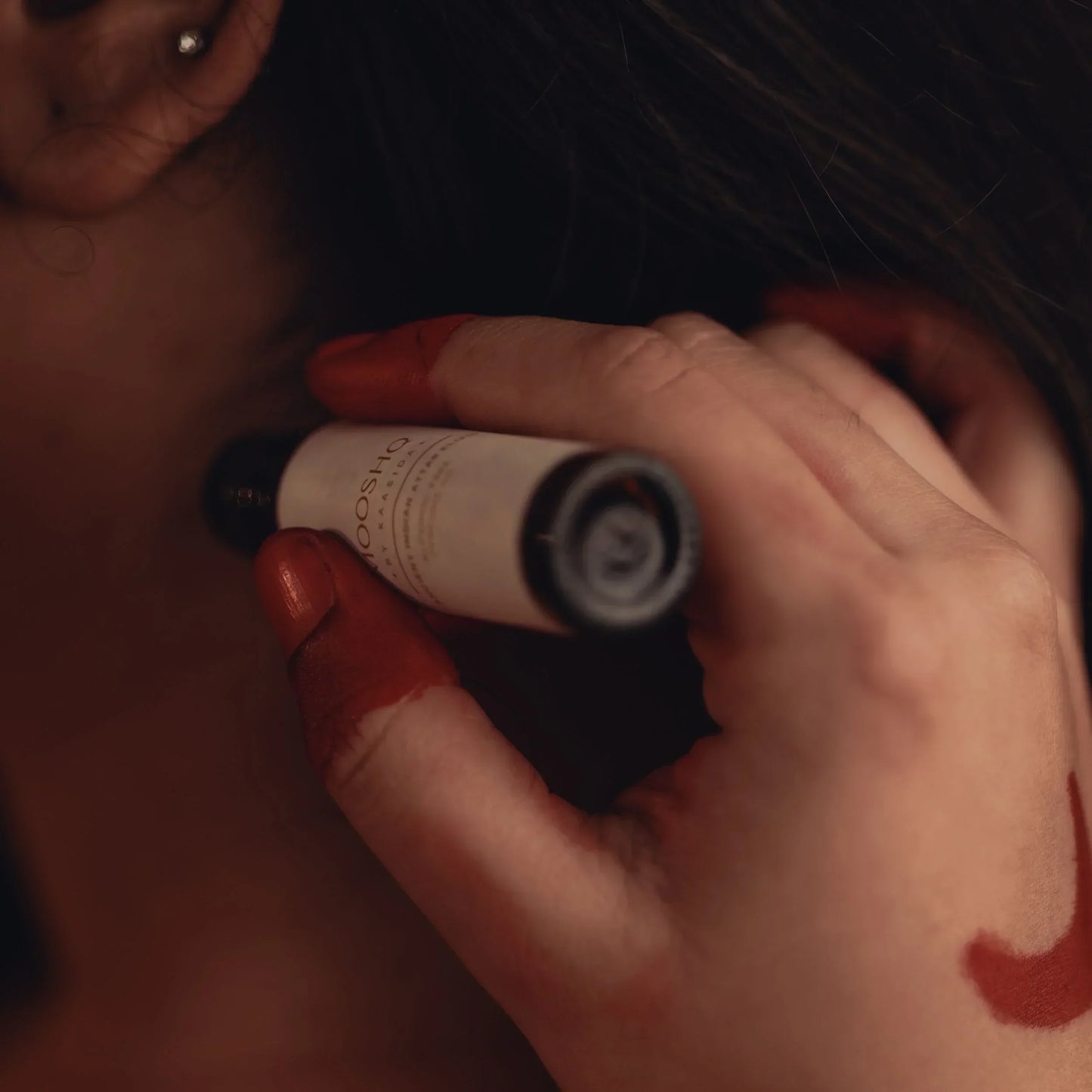 Woman applying a perfume oil from a small bottle to her skin