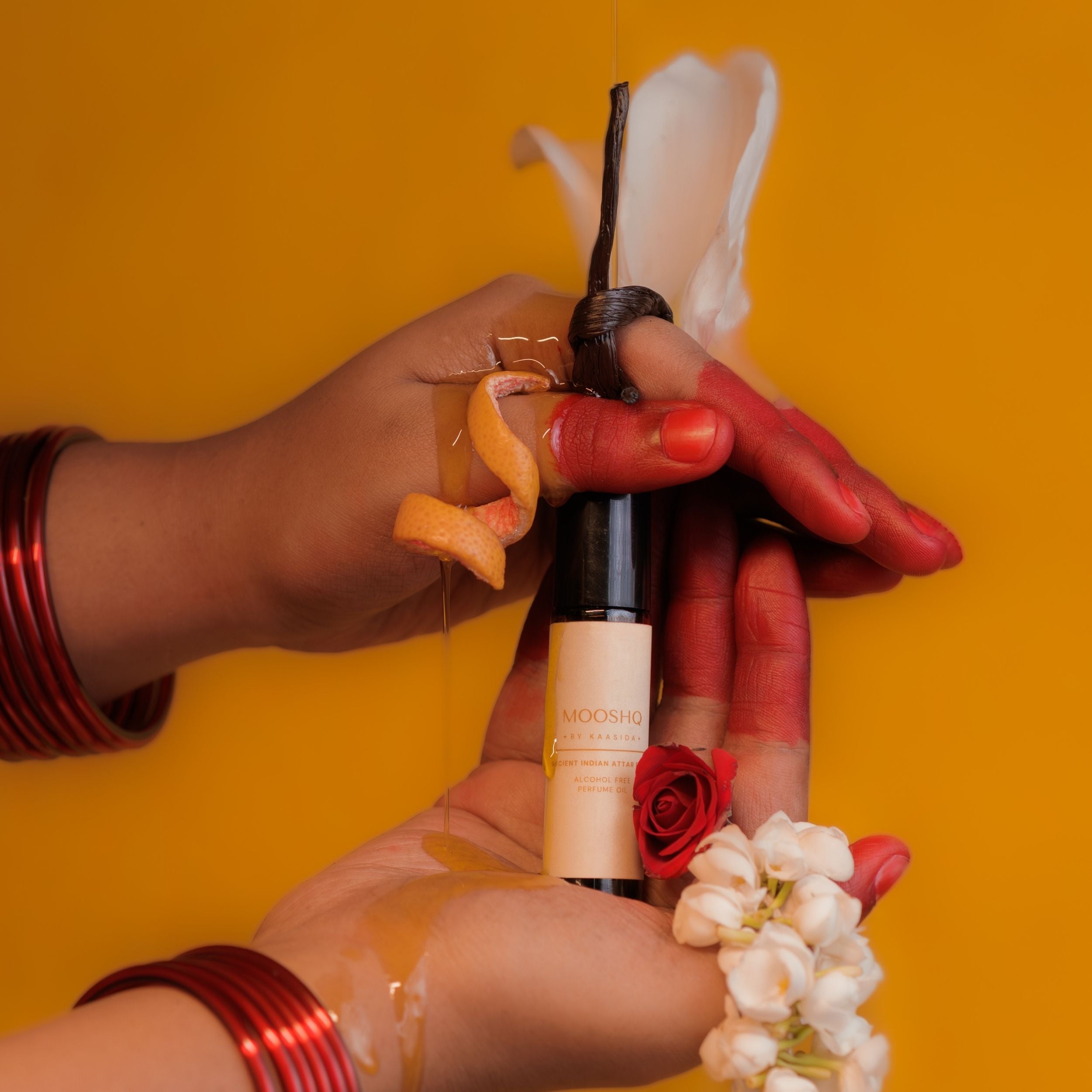 Hand holding a Perfume oil bottle against a yellow background
