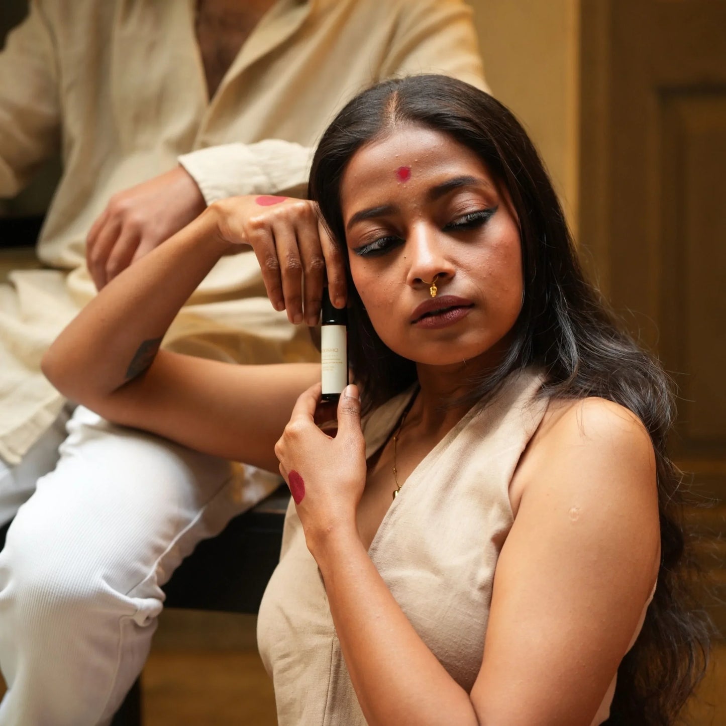 Woman holding Mooshq Perfume Oil sitting next to a man