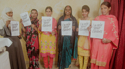 Female artisans of India holding a banner that says 'I made your clothes'