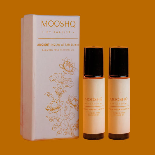 Two bottles of MOOSHQ alcohol-free perfume oil bottles by Kaasida on an orange background