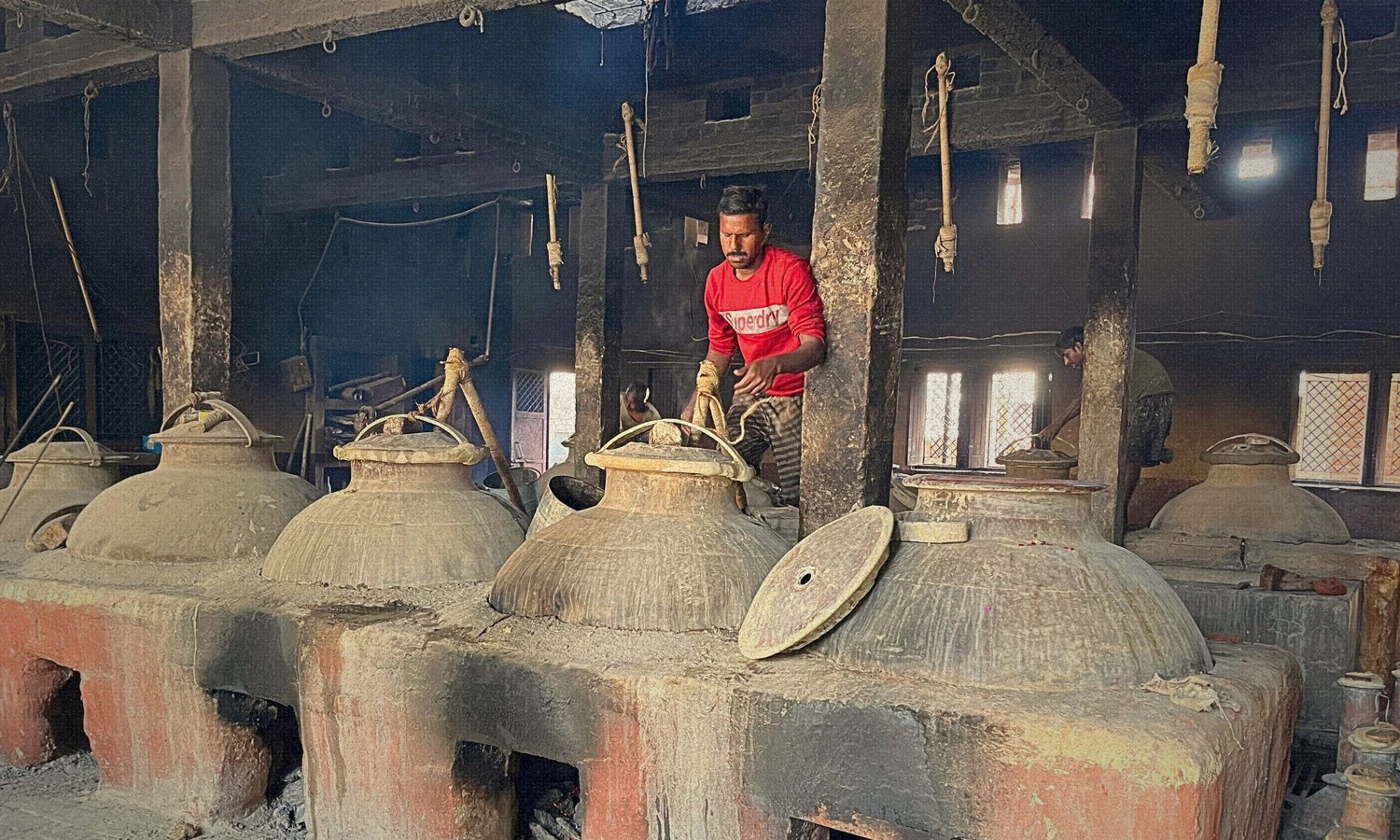 Person making traditiona Indian attar perfume oil in large clay ovens using the age-old deg-bhapka method.