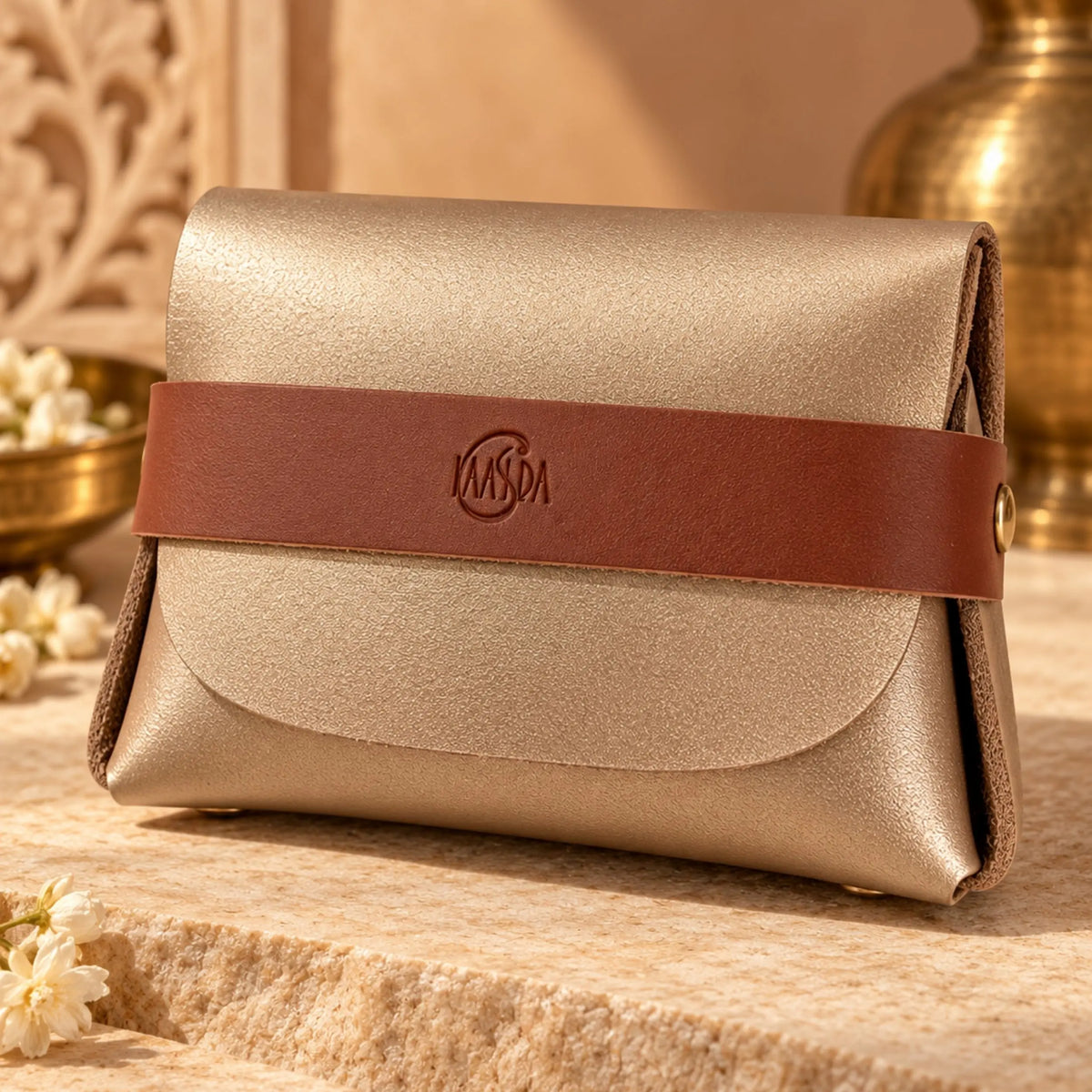 Gold pouch with brown strap that say Kaasida