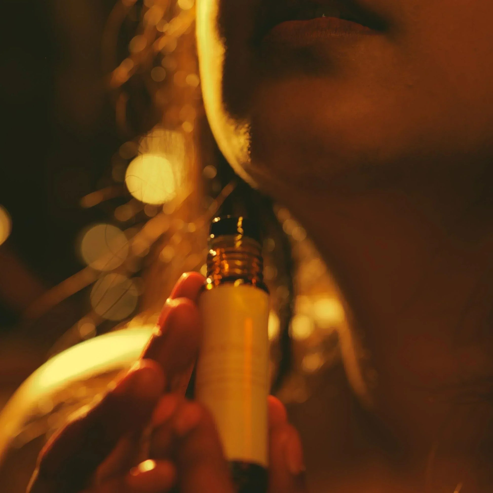 Close-up of a woman holding a small perfume bottle with a blurred background