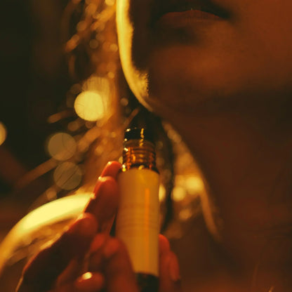 Close-up of a woman holding a small perfume bottle with a blurred background