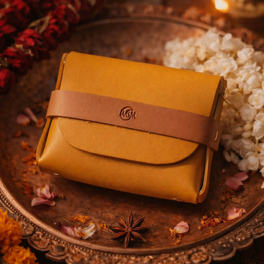 Yellow vegan leather pouch with brown strap on a decorative plate with flowers and spices