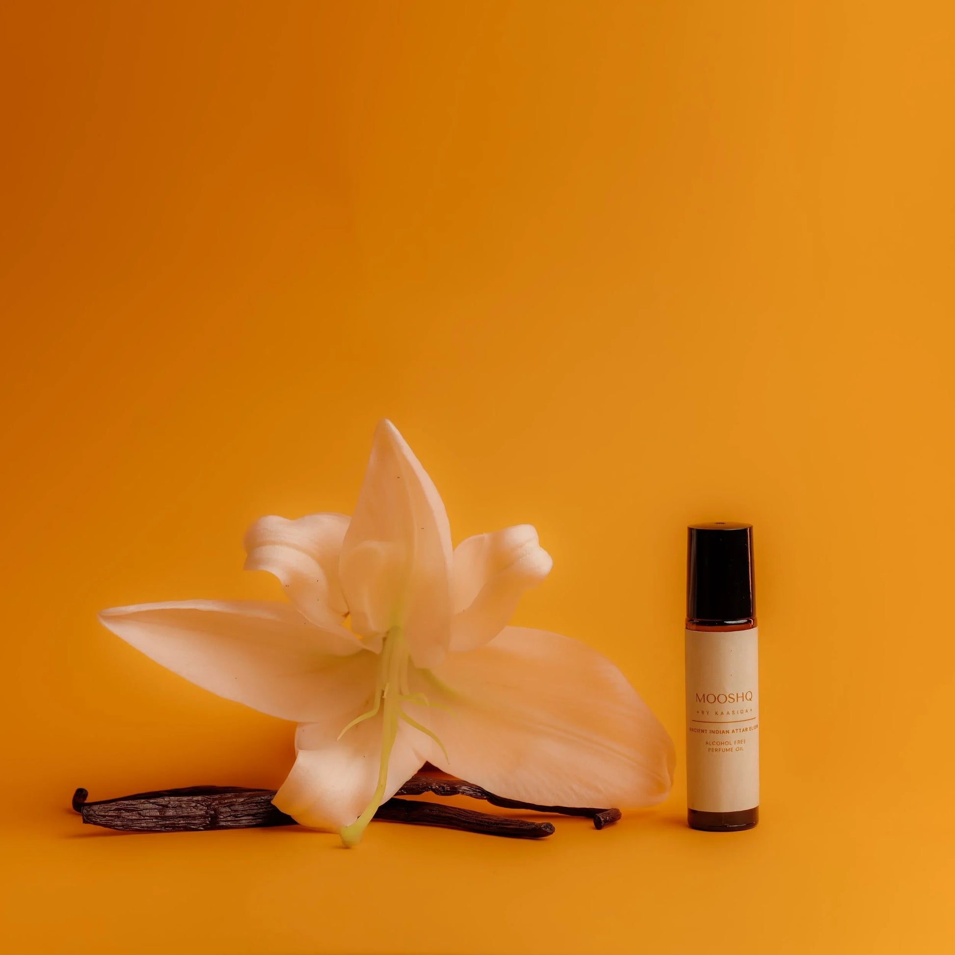 Lily flower and vanilla beans with a Perfume Oil bottle on a yellow background