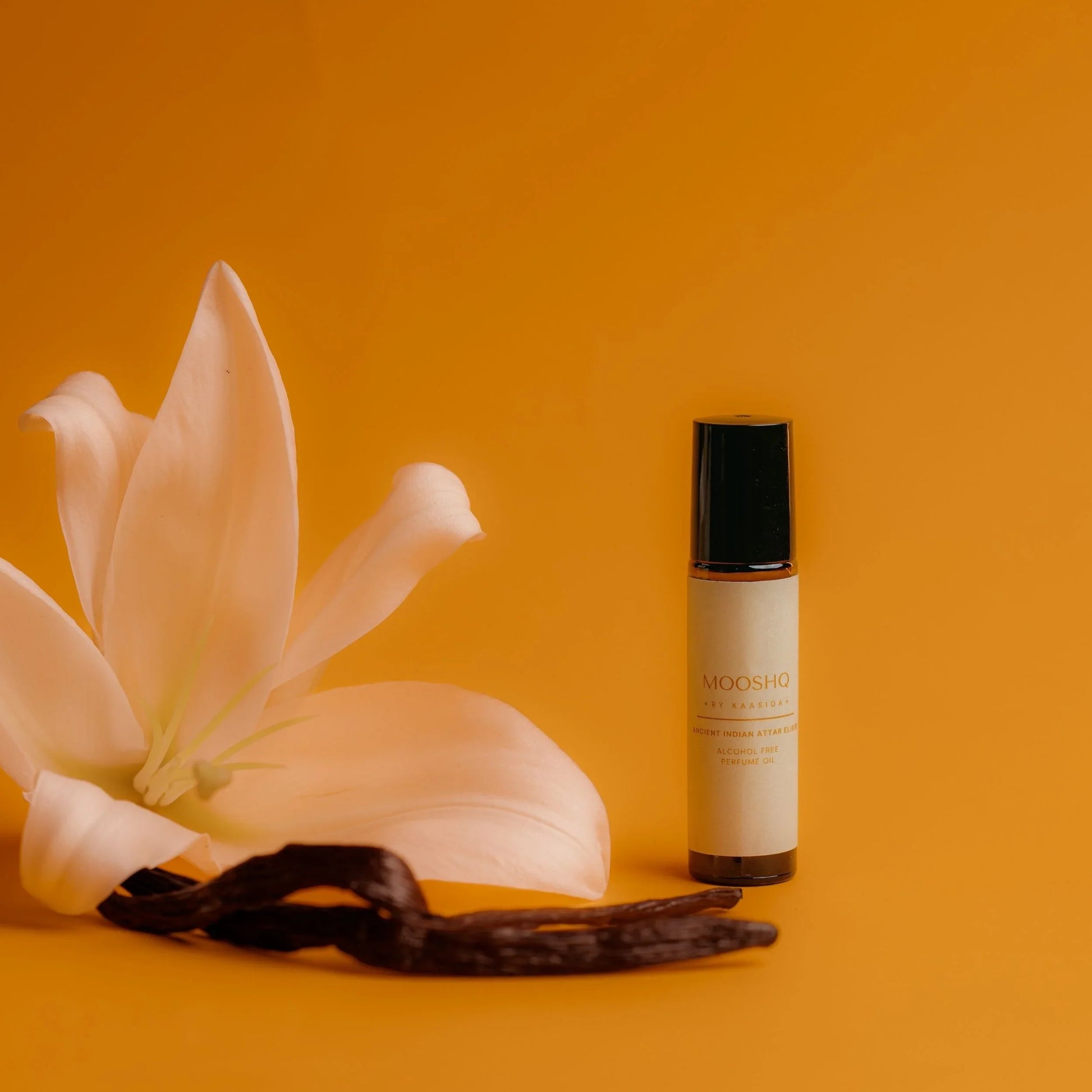 Perfume Oil bottle with lily flower and vanilla beans on an orange background
