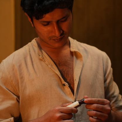Man holding a Mooshq Perfume Oil with a warm-toned background