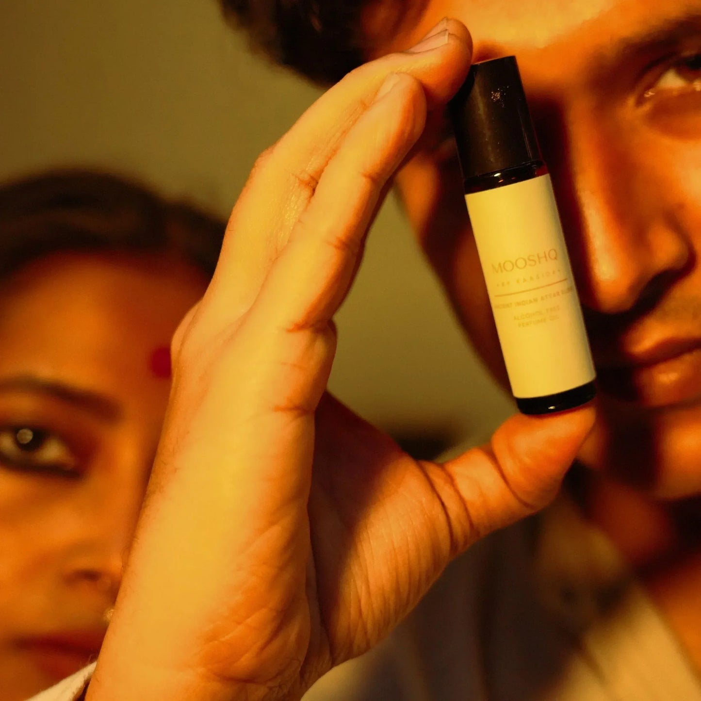 Man holding a Mooshq perfume oil close to their face.