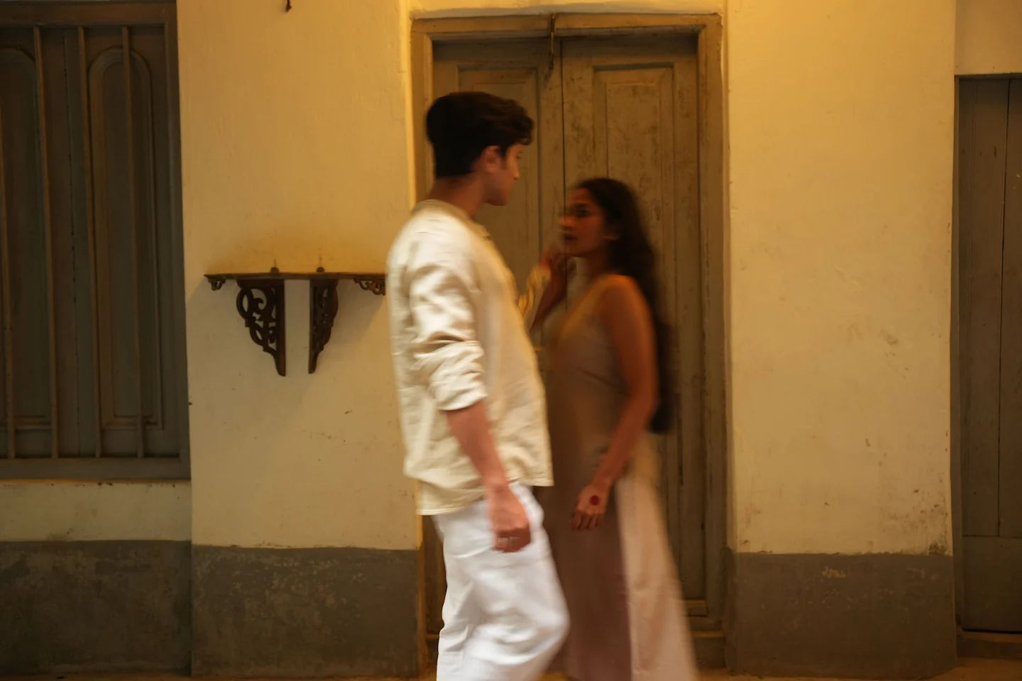 A man and a woman standing in a narrow alleyway with a building wall behind them 