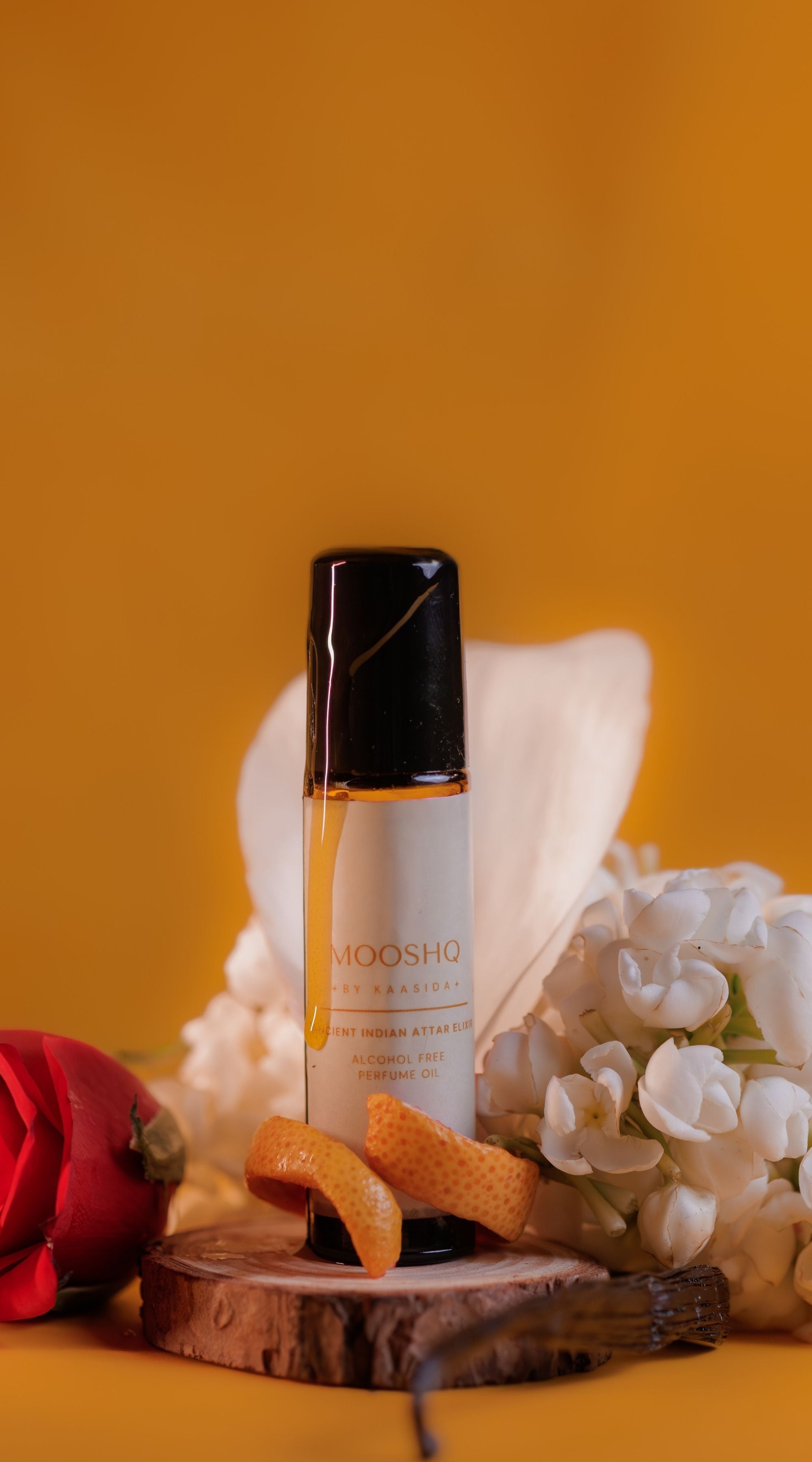 Mooshq Perfume Oil with flowers and a red flower on a yellow background
