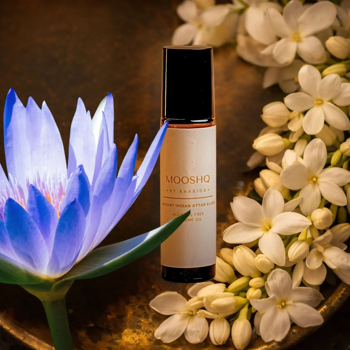 Mooshq Perfume oil bottle with a blue lotus and jasmin flowes on a wooden surface
