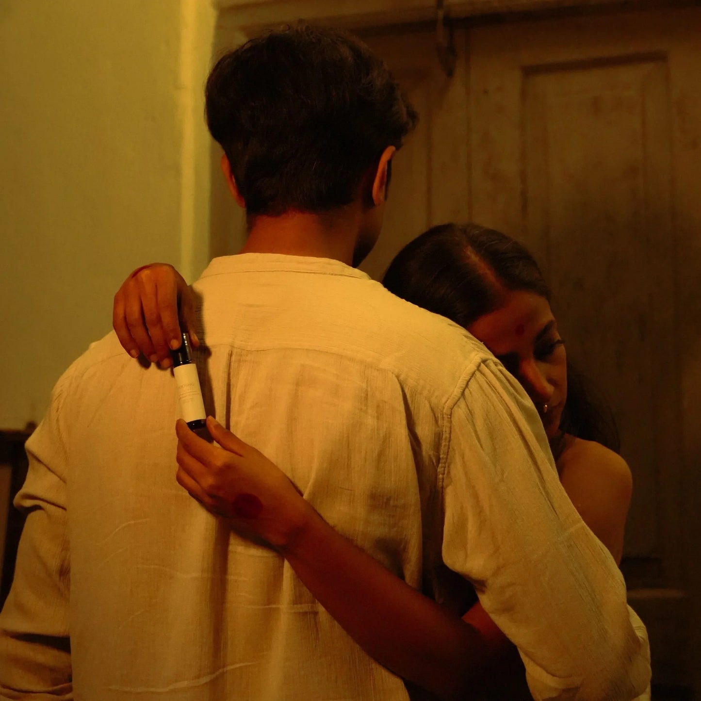 Two people embracing in a warmly lit room.