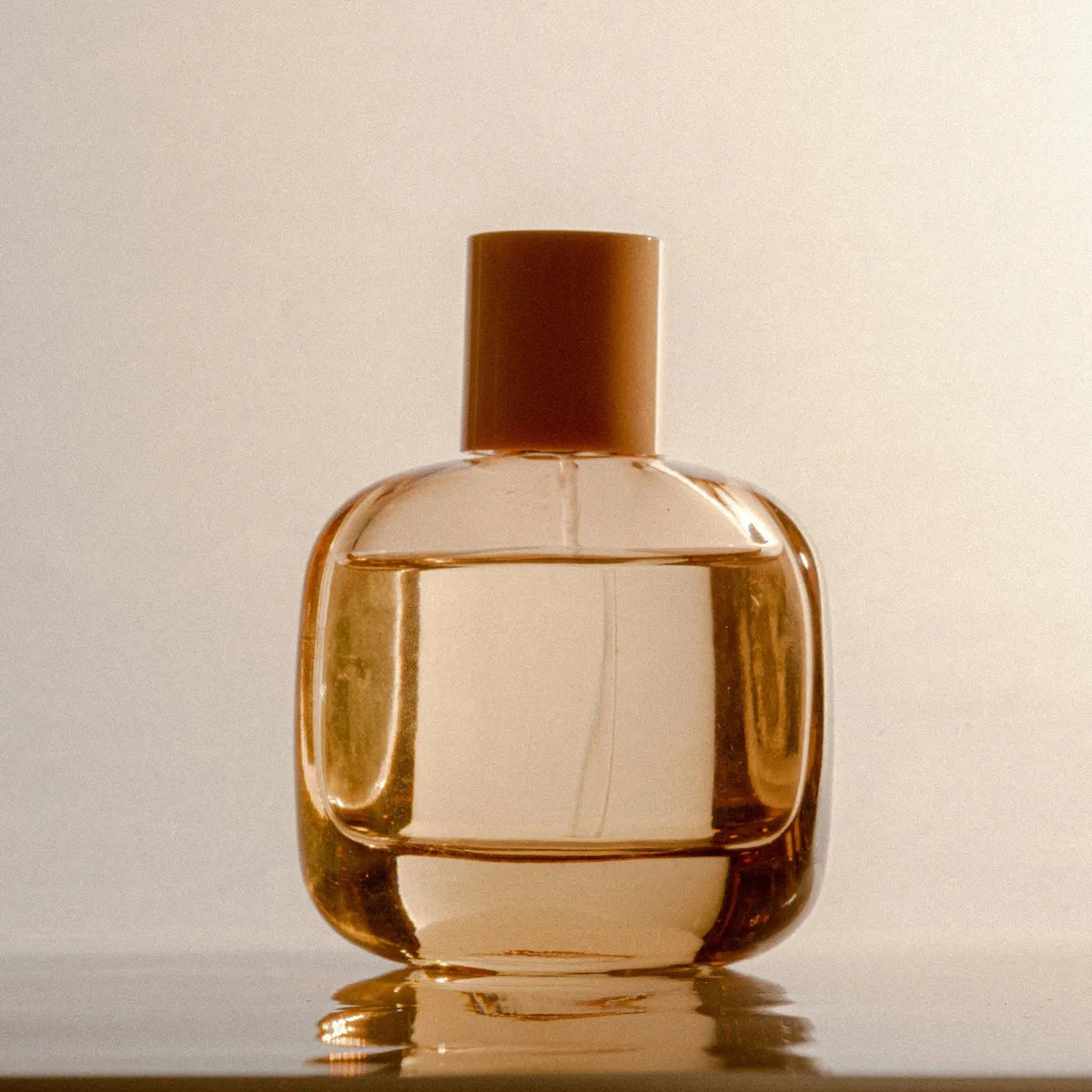 Glass perfume bottle with gold cap on a light background