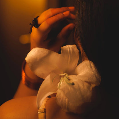 Close-up of a woman's back with a white lily flower with a blurred background